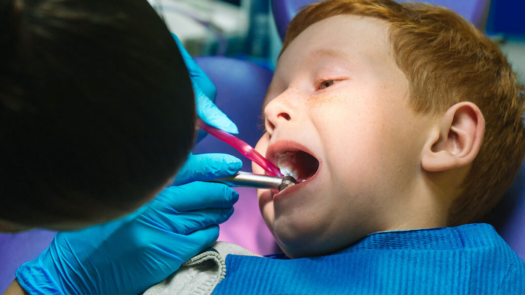 dentist looking into the mouth of a little boy